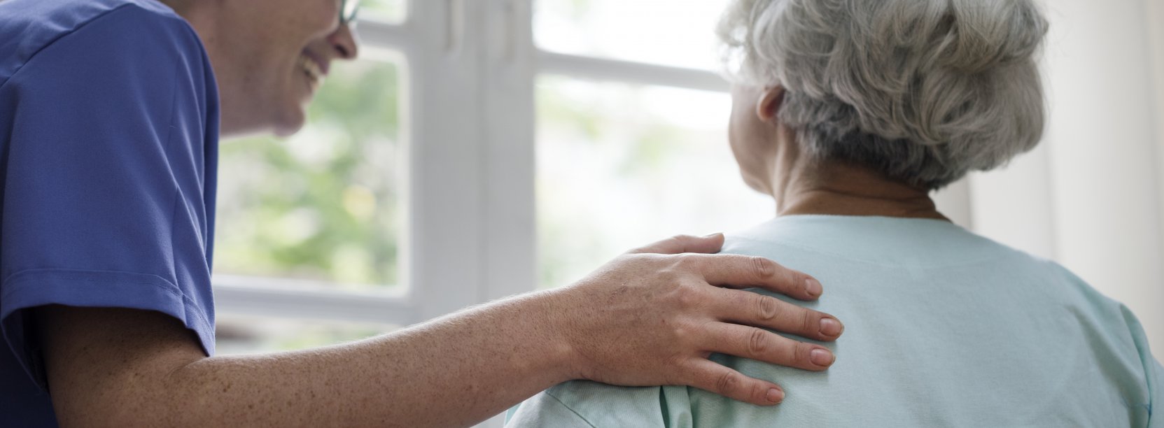 Opiekunka z seniorką patrzącą w okno 