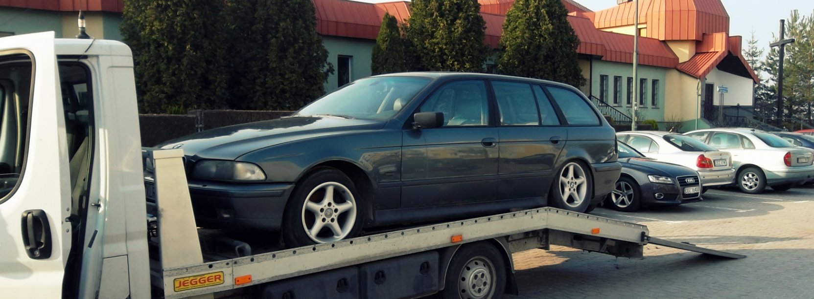 Auto stojące na lawecie, w drugim planie budynek