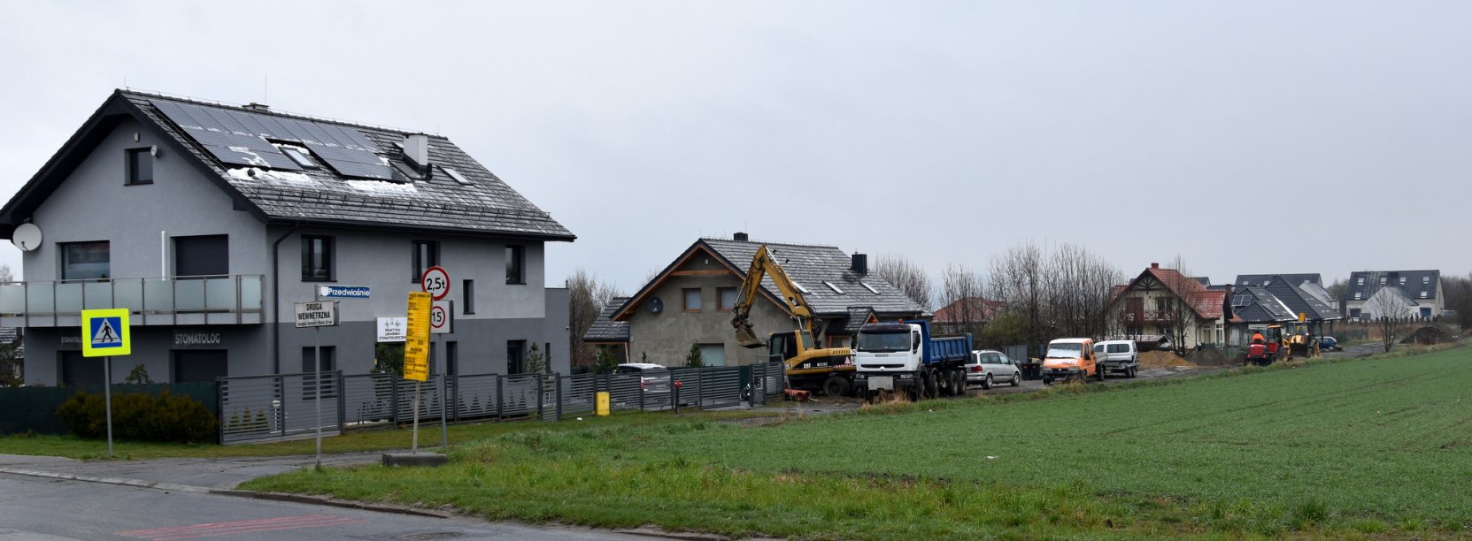 Widok na domy jednorodzinne i maszyny budowlane pracujące na drodze 