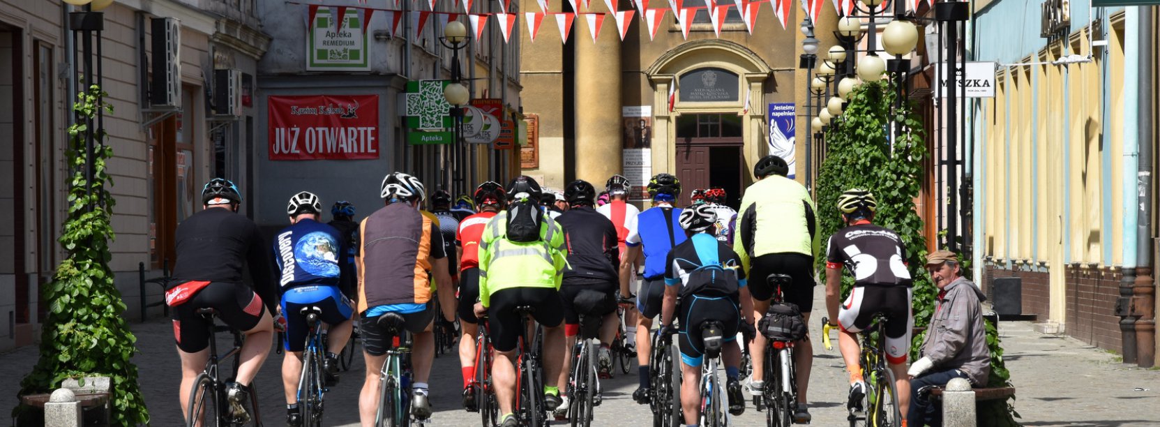 Grupa rowerzystów jadąca ulicą, po bokach kamienice