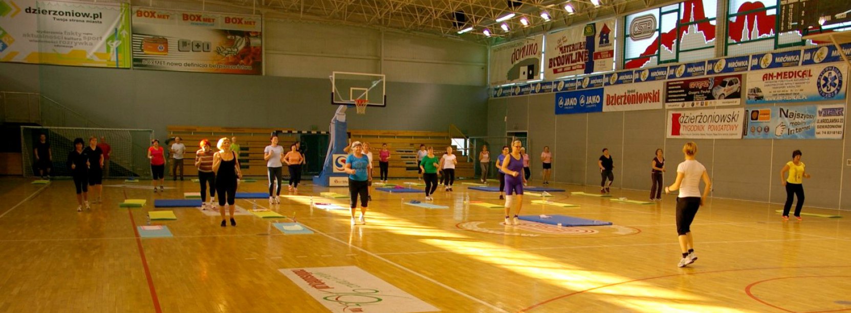 Hala sportowa od środka i ćwicząca w niej grupa osób 