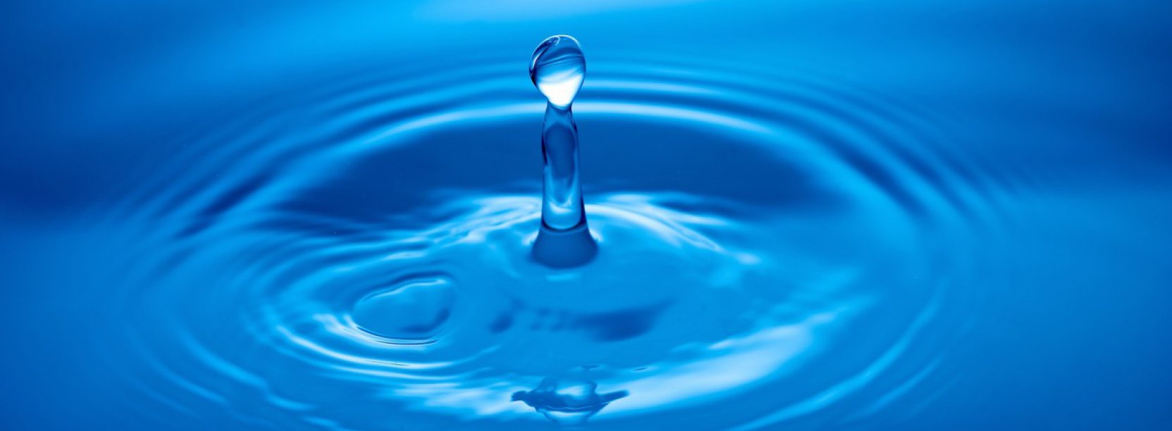 Kropla spadająca na taflę wody, niebieskie tło