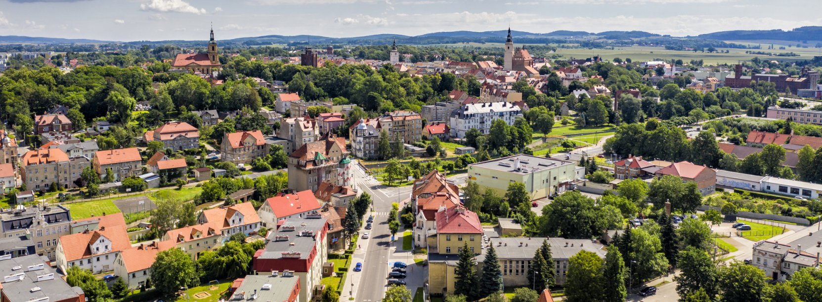 Dzierżoniów z górym, zachmurzone niebo, w drugim planie góry