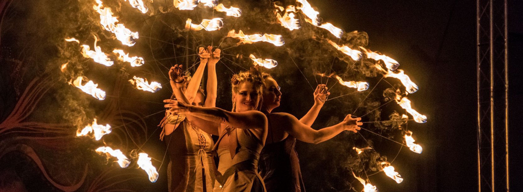 Noc, trzy kobiety tańczące z ogniem