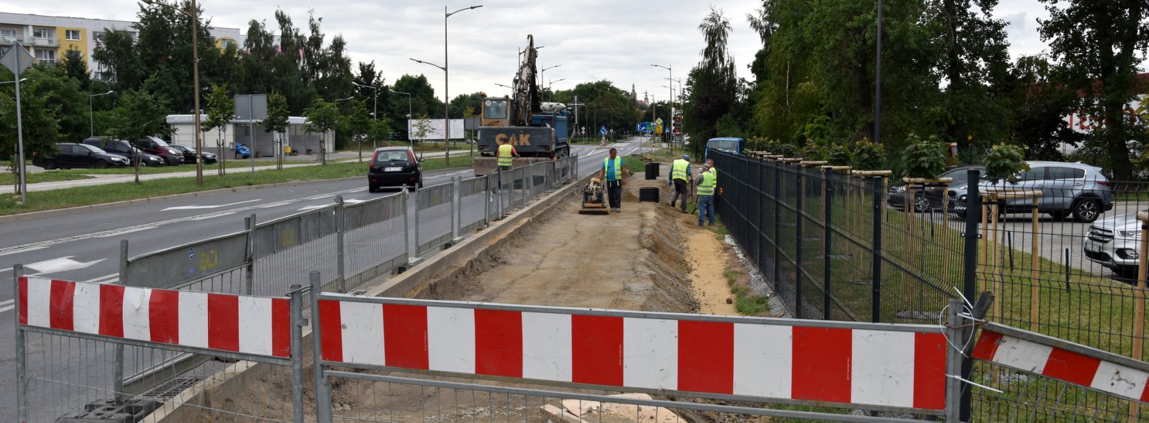 Ogrodzone miejsce przy drodze, pracownicy budujący chodnik