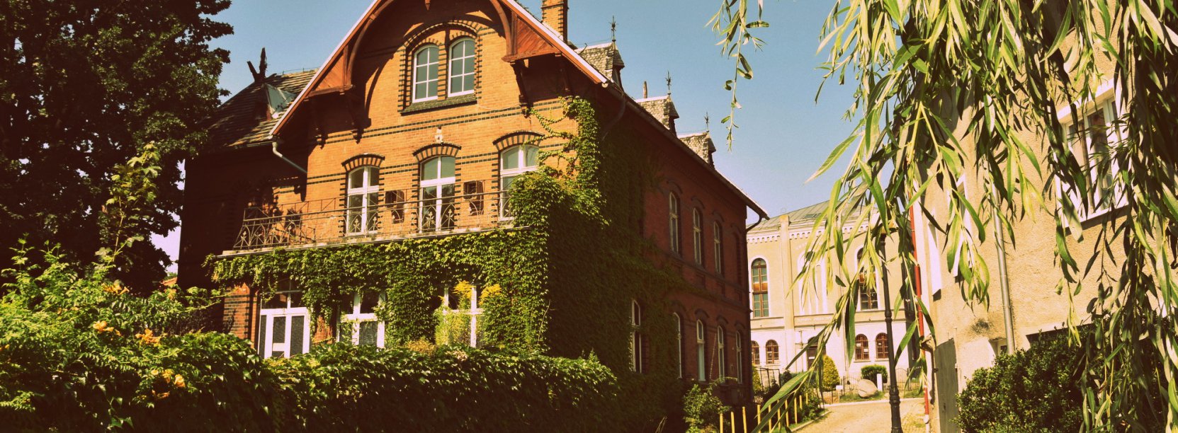 Budynek z czerwonej cegły otoczony zielenią