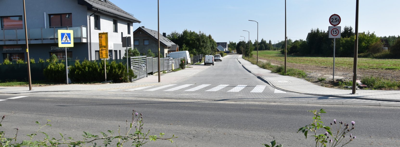 Widok na droge z kostki betonowej, obok budynki jednorodzinne