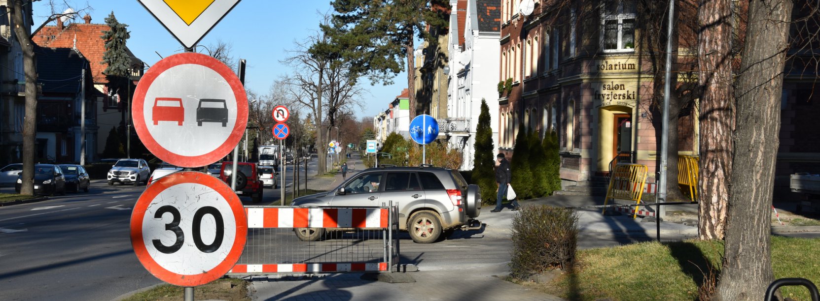 Widok chodnika i drogi, na pierwszym planie znaki drogowe