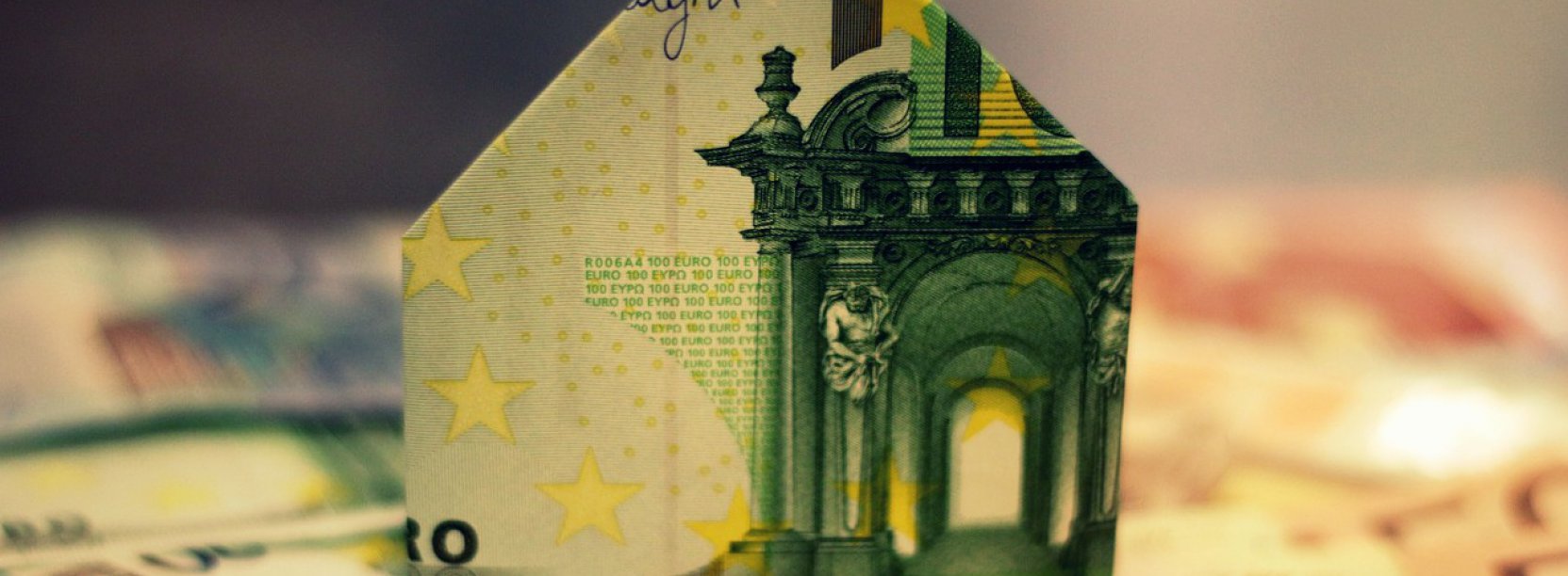 Banknot eur złozony w domek stojący na leżacych banknotach