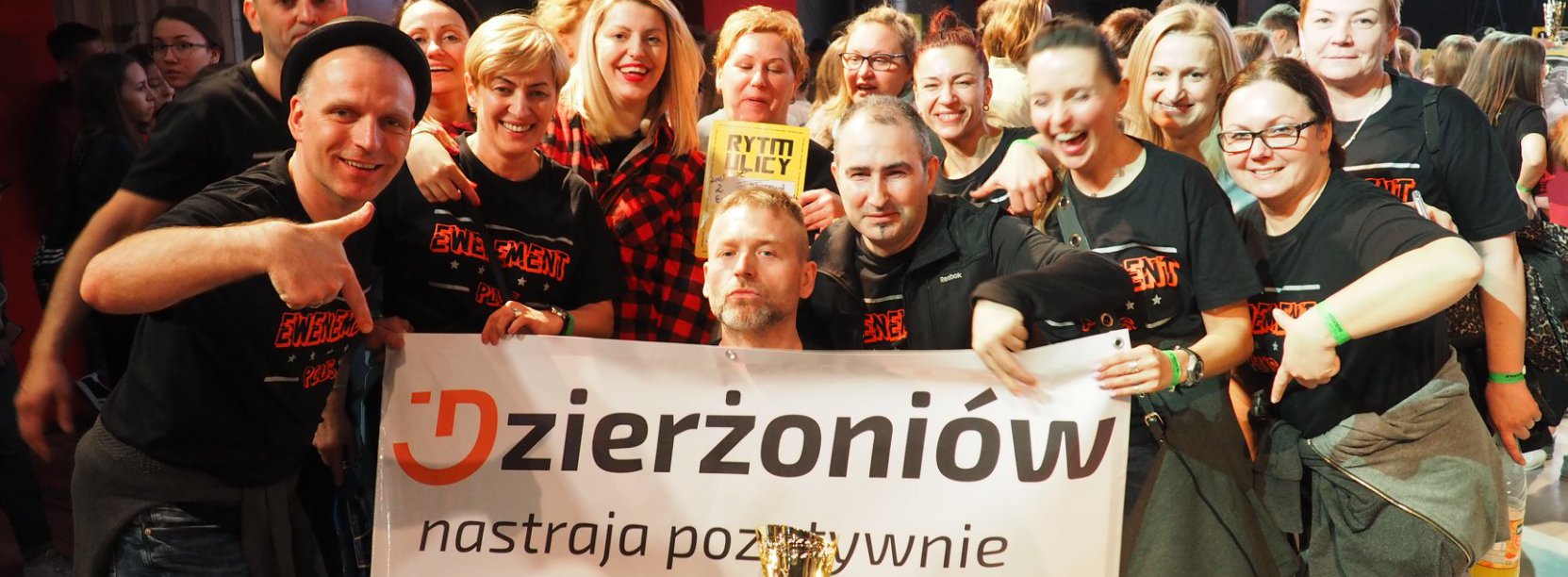 Usmiechnięta grupa trzymająca baner z napisem Dzierżoniów nastraja pozytywnie