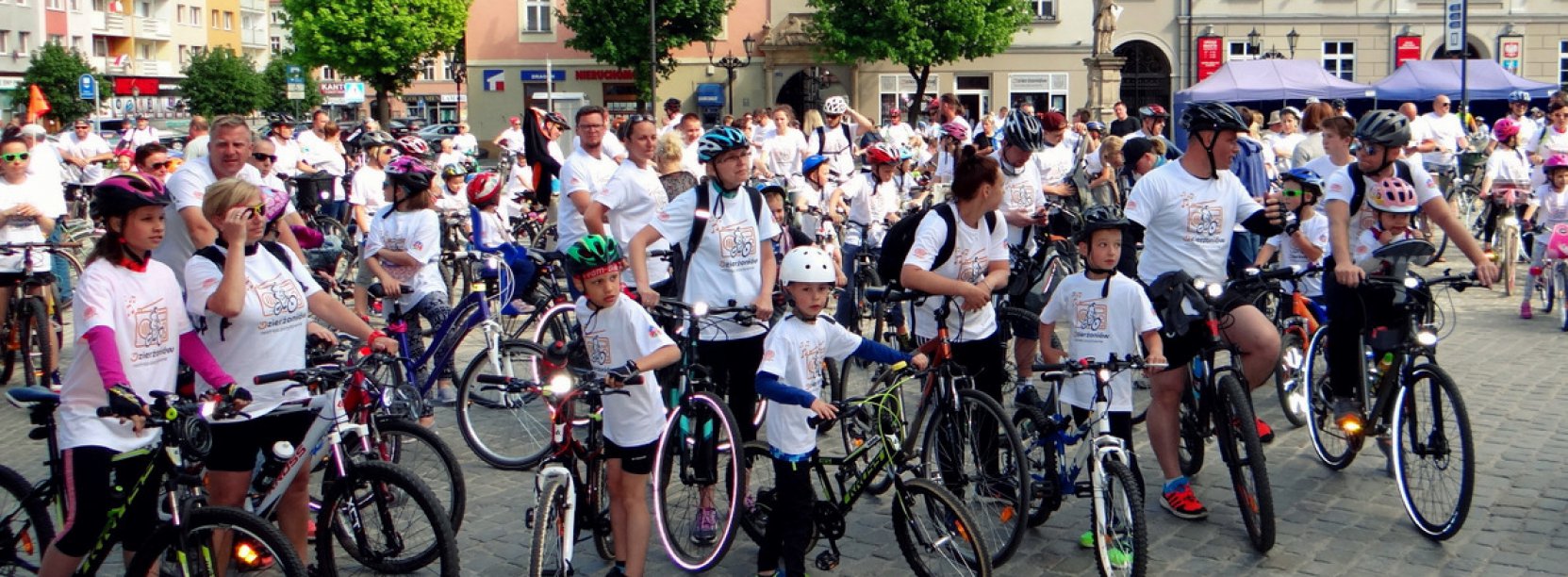 Duża grupa dorosłych i dzieci z rowerami na rynku
