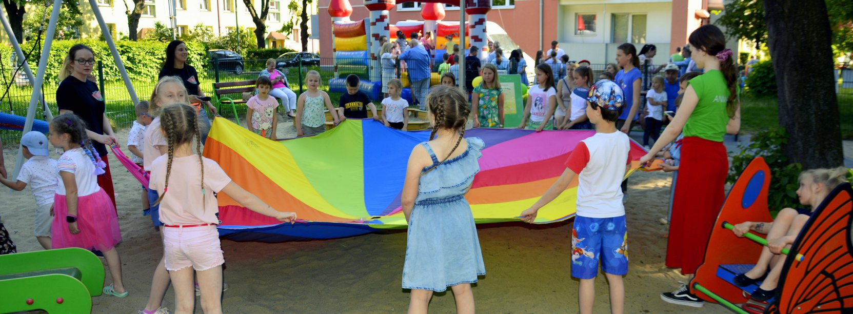 Dzieci trzymające kolorową tkaninę, plac zabaw 