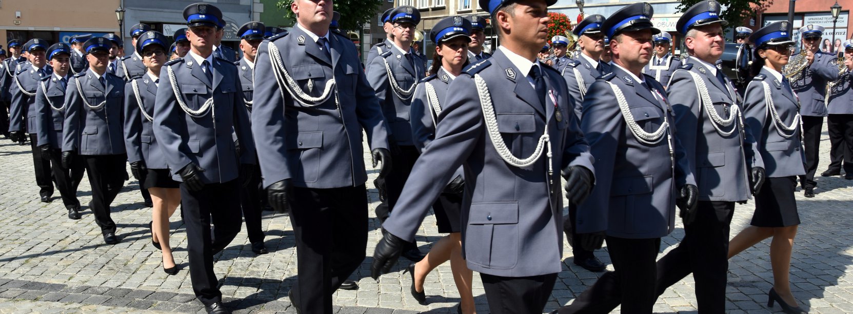 Plicjanci idący w szyku przez rynek 