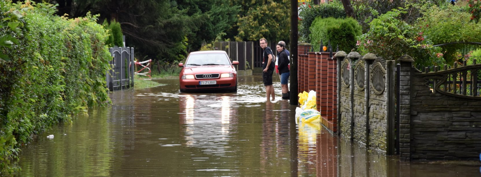 Zalana droga i jadące przez nią auto