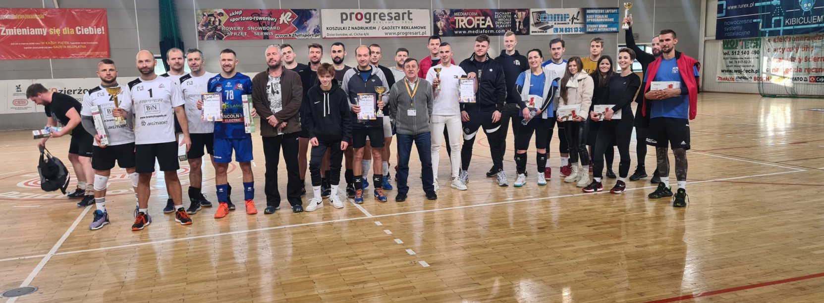 zawodnicy z pucharami w hali sportowej