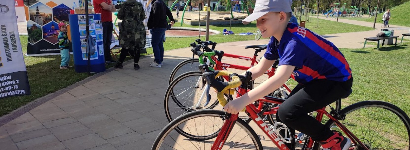 Młody chłopak na rowerze, w tle pllac zabaw