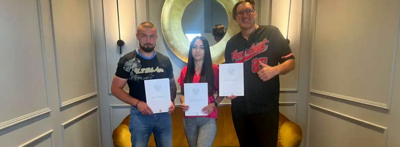 Dwóch mężczyzn i kobieta w środku, wszyscy trzymają w rękach dyplomy