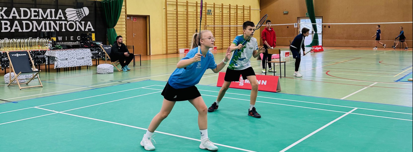 Dziewczyna i chłopak grający w badmingtona w hali sportowej