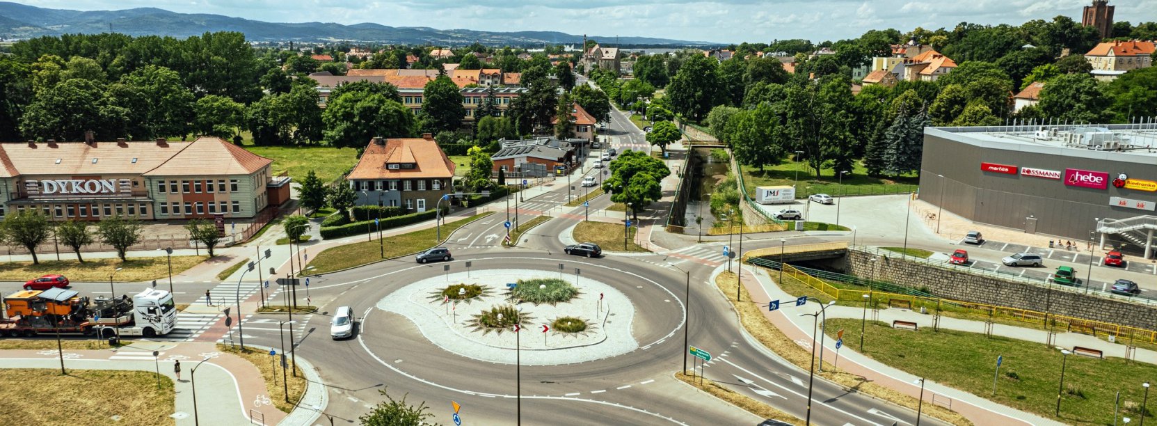 Duże rondo widziane z góry, obok budynki, na drugim planie dużo zieleni