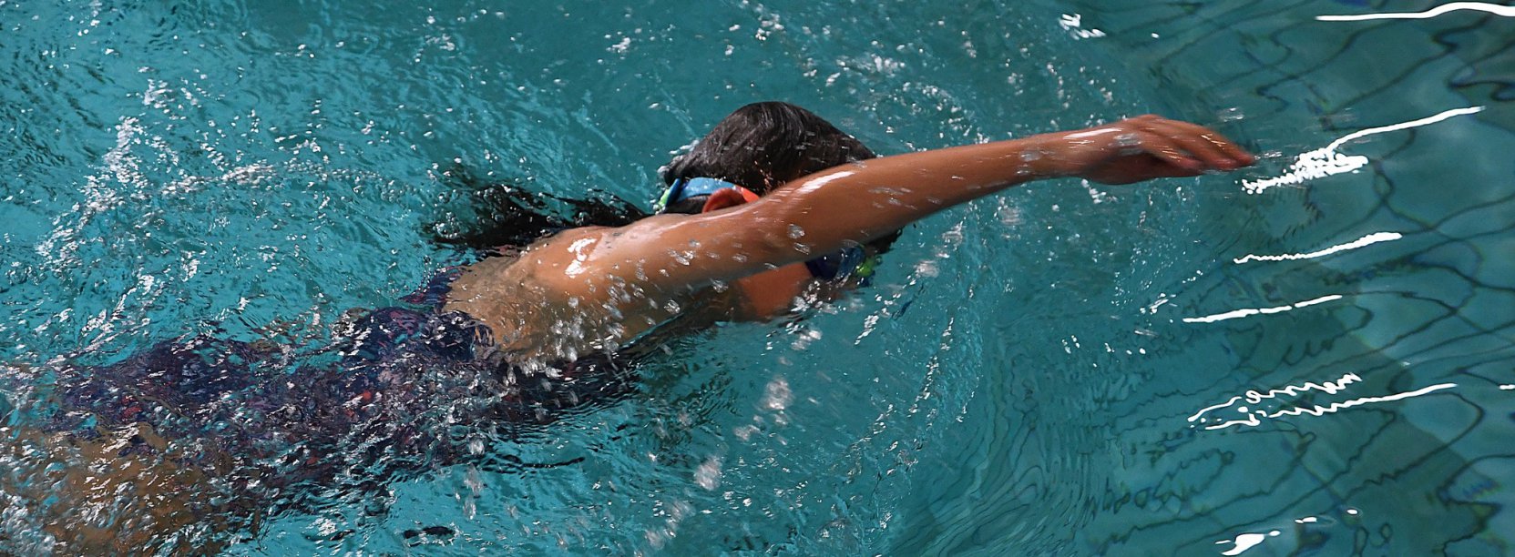 Dziewczyna podczas pływania, z wysunięta do przodu ręką. Zdjęcie z góry 