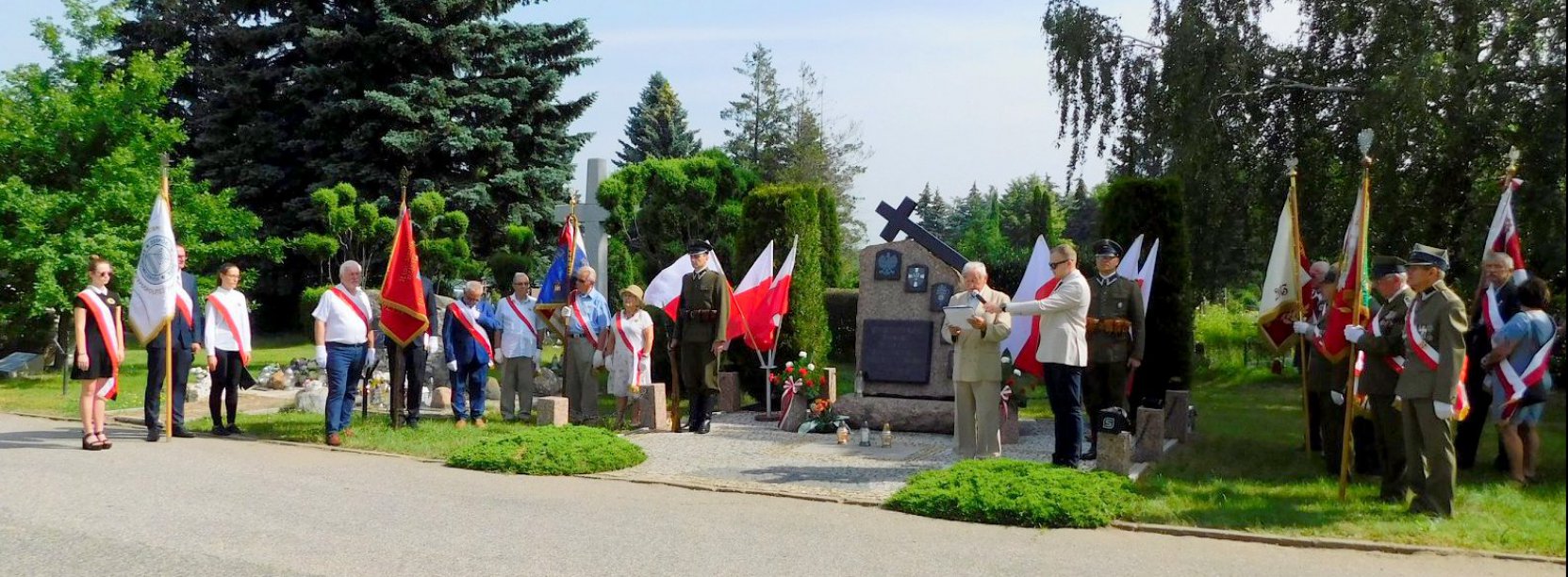 Cmentarny obelisk, ludzie z flagami Polski, żołenierze i kombatanci w mundurach 