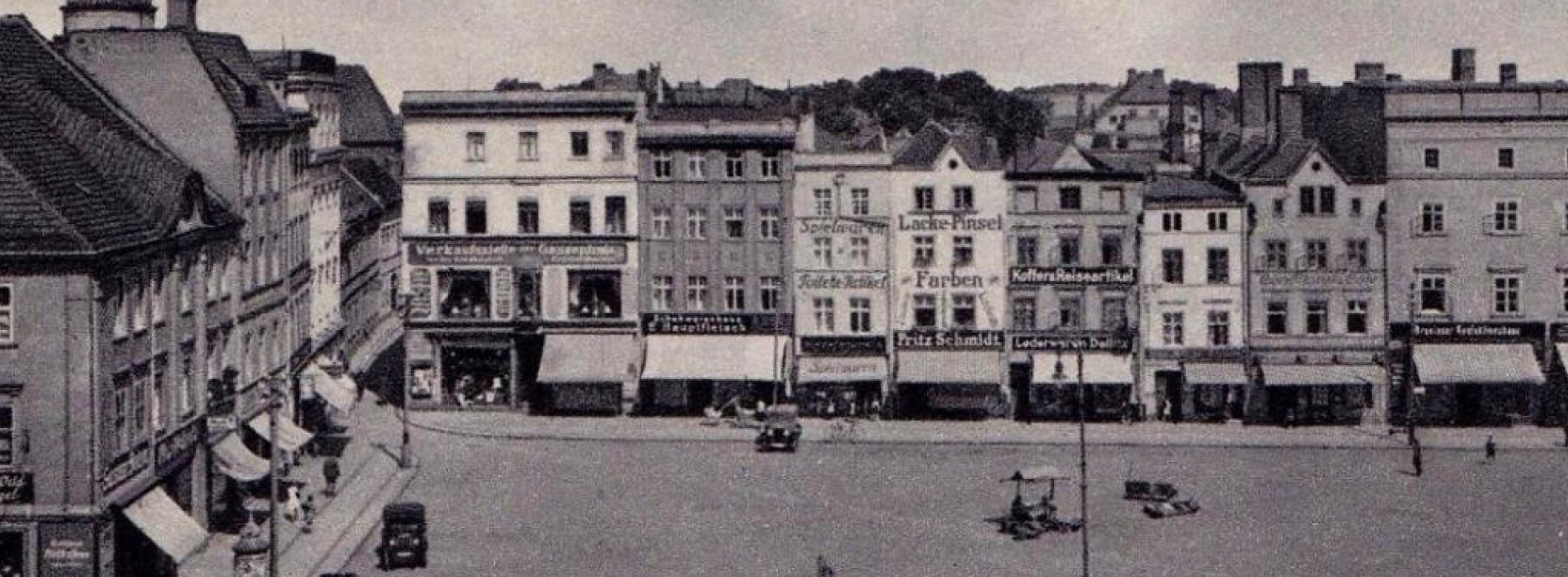 Przedwojenny rynek, kamienice, na parterach markizy, na rynku stojące stare automobile