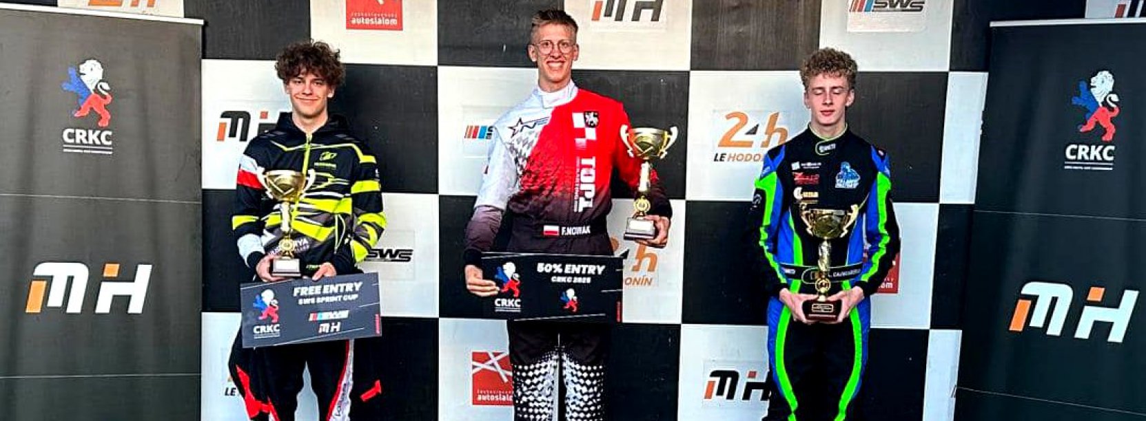 Trzech młodych kierowców w kombinezonach do ścigania na podium