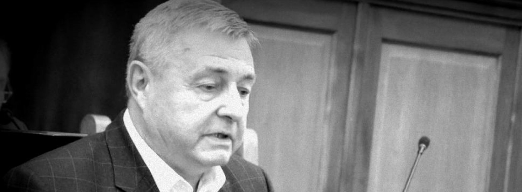 Czarno-białe zdjęcie na którym jest Janusz Moskalski podczas sesji rady miasta