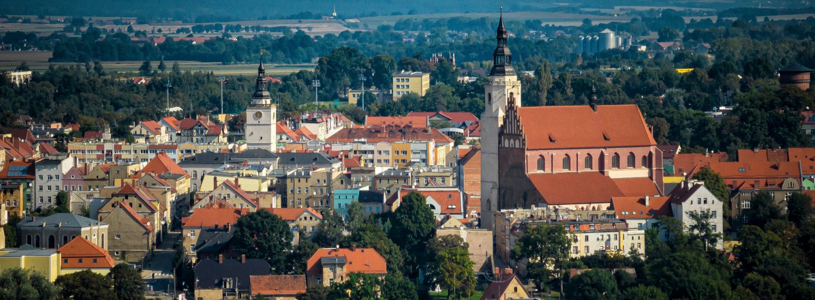 Starówka Dzierżoniowa z lotu ptaka, na pierwszym plane duży średniowieczny kościół, w tle góry