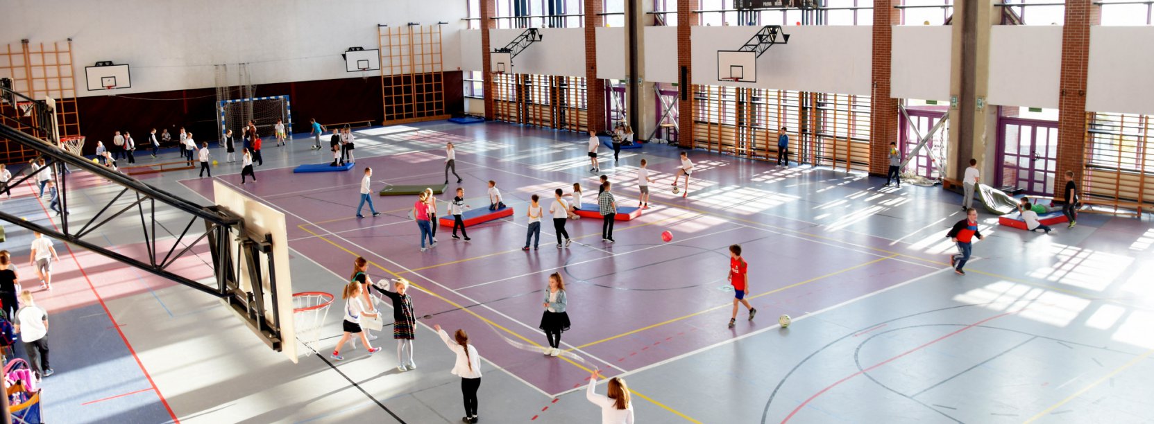 Hala sportowa i uczniowie ćwiący w niej uczniowie 
