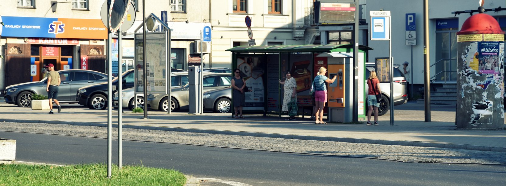 Przystanek autobusowy, na przystanków kilka osób czekających na autobus