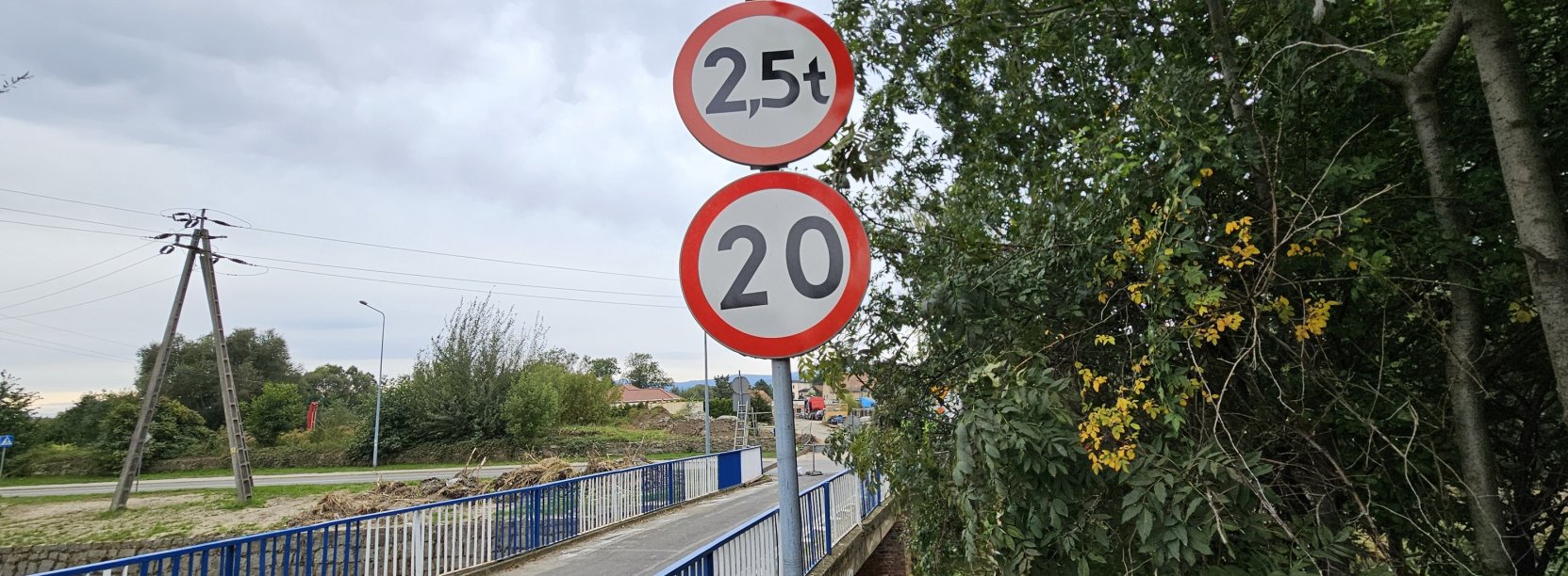 Mały most, po bokach biało-niebieski barierki, przed mostem znak ograniczenia prędkości do 20 km/h i ograniczenia wjazdu aut powyżej 2,5 tony 