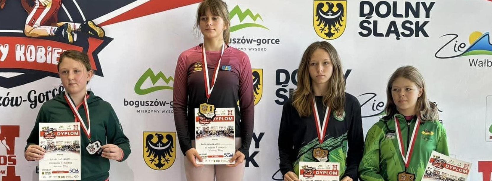 Cztery młode zapaśniczki stojąće na podium, każda trzyma dyplom
