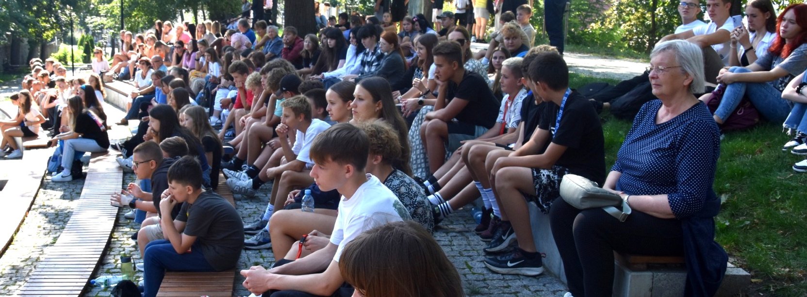Młodzi ludzie siedzący na ławkach amfiteatru w parku