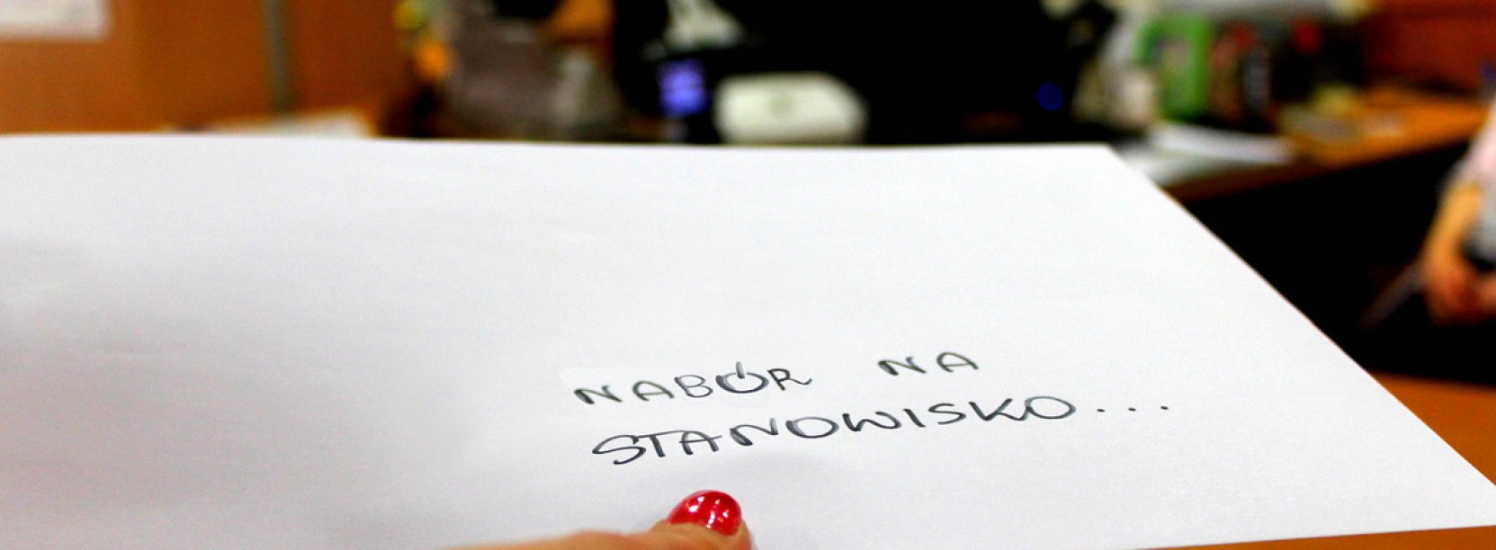 Dłoń trzymająca białą kopertę z napisem "Nabór na stanowisko..."