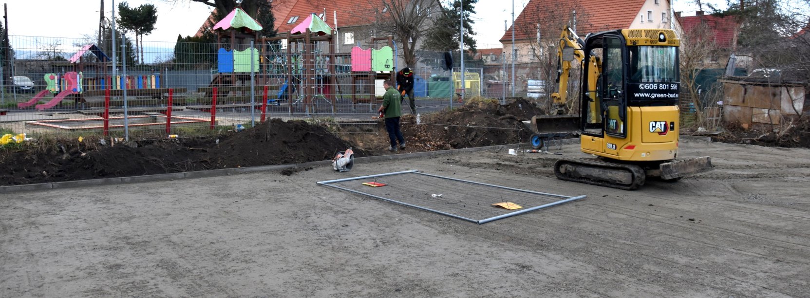 Utwardzony teren pod boisko do koszykówki, w tle plac zabaw i budynki mieszkalne