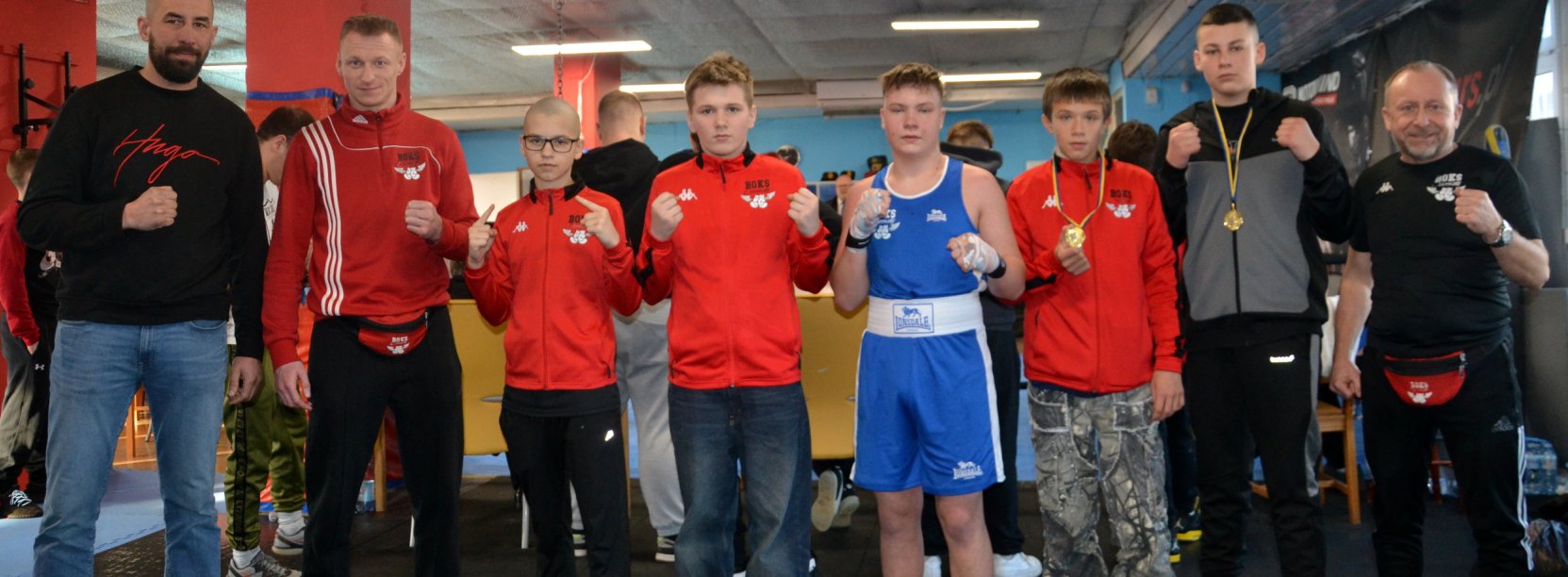 Zawodnicy klubu Boks Ciszewski na współnych zdjęciu, niektózy z medalami zawieszonymi na szyi, po bokach trenerzy