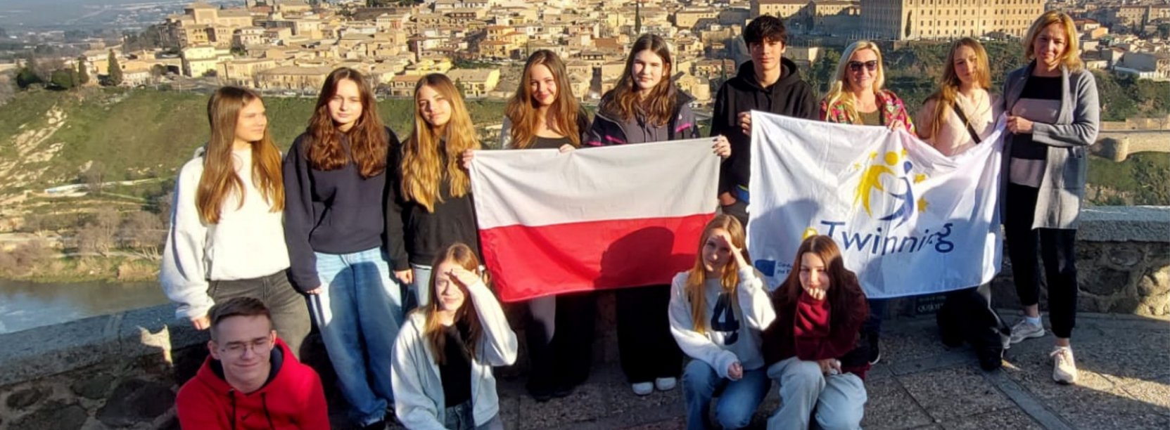 Grupowe zdjęcie uczniów SP9 z flagą Polski na tle panoramy zabytkowej starówki