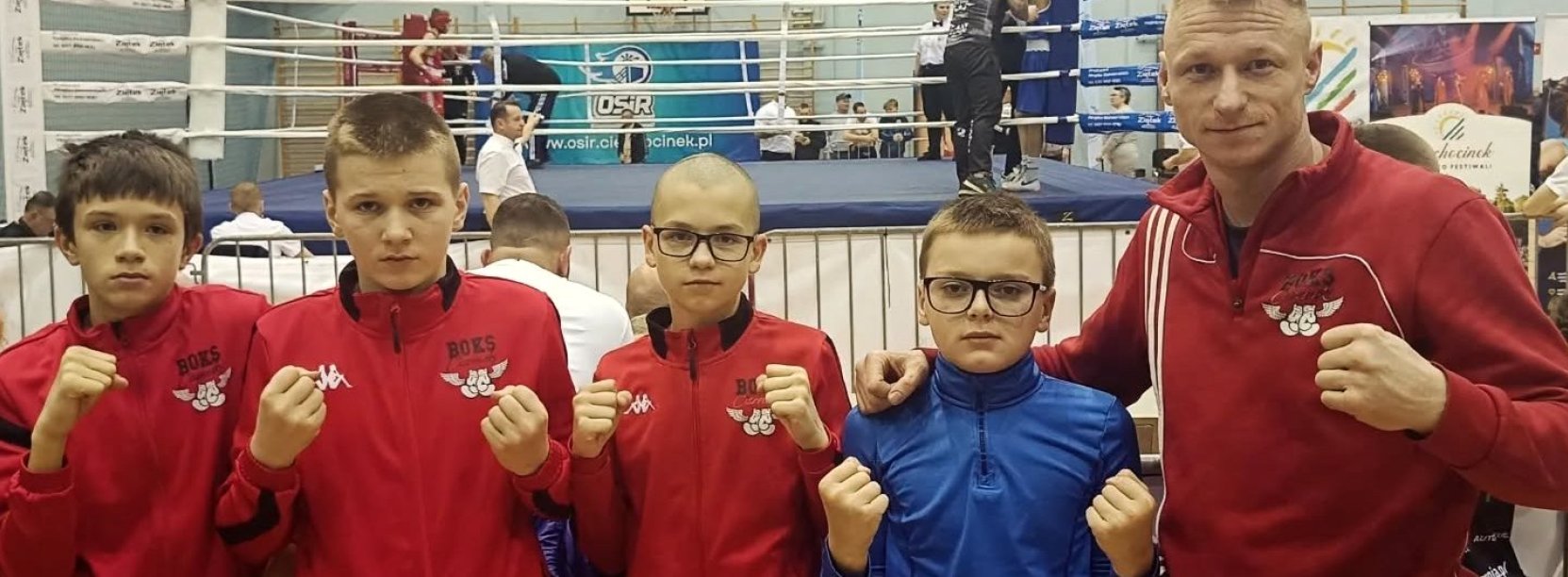 Czwórka zawodników i trener na wspólnym zdjęciu, z tyłu ring