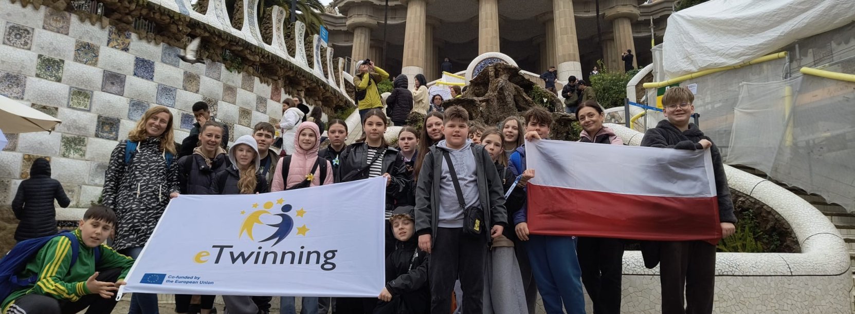 Grupowe zdjęcie uczniów, cześć z nich trzyma dużą flagę Polski