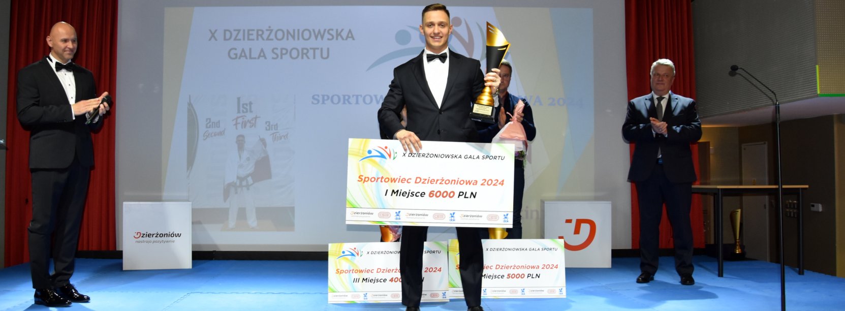 Maksymilian Palej na scenie z pucharem i symbolicznym czekiem
