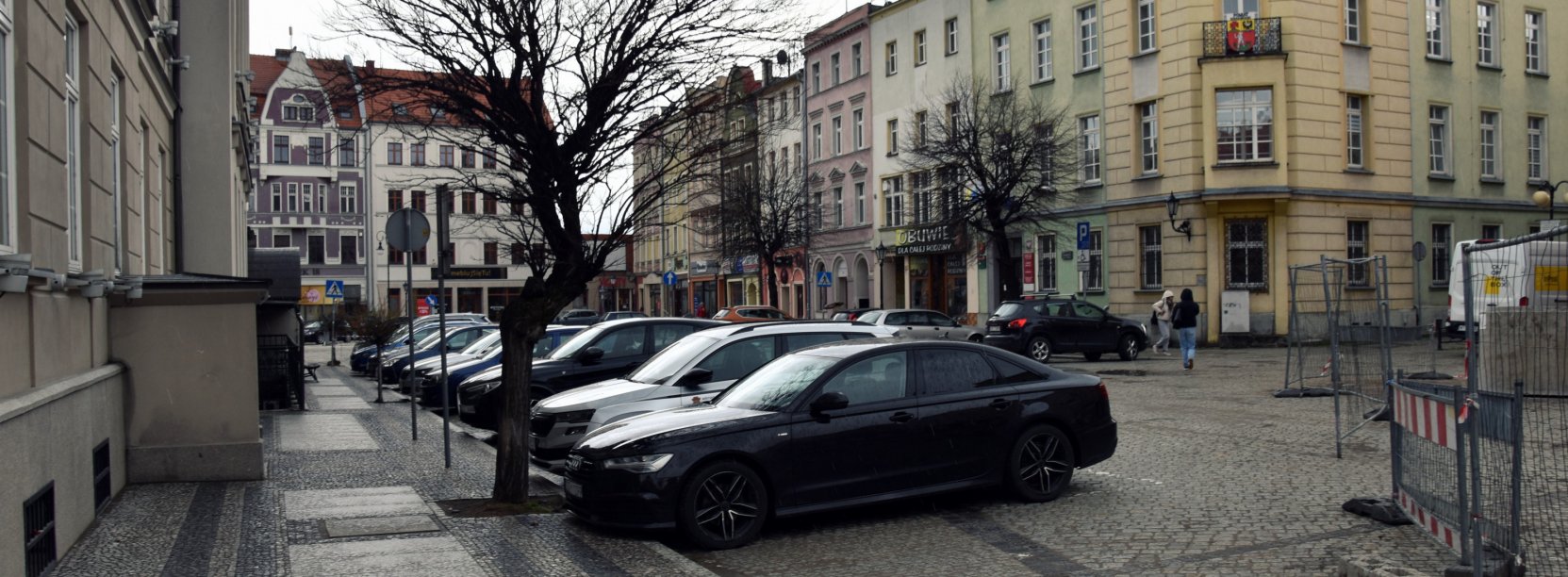 Fragment dzierżoniowskiego rynku, zaparkowane samochody, na drugim planie kamienice