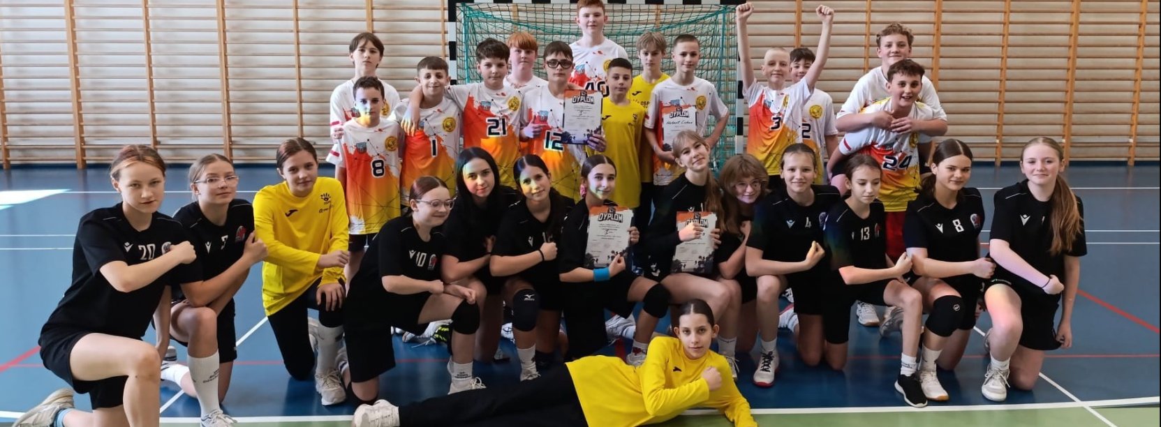Grupowe zdjęcie uczniów szkoły w sportowych strojach w sali gimnastycznej