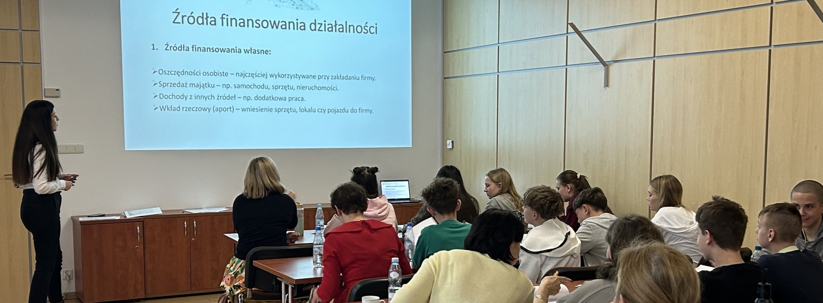 Uczniowie siedzący w ławkach podczas wykładu o przedsiębiorczości