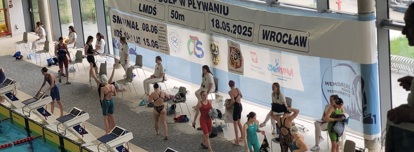 Zawodnicy przy krawędzi basenu przygotowują się do startów