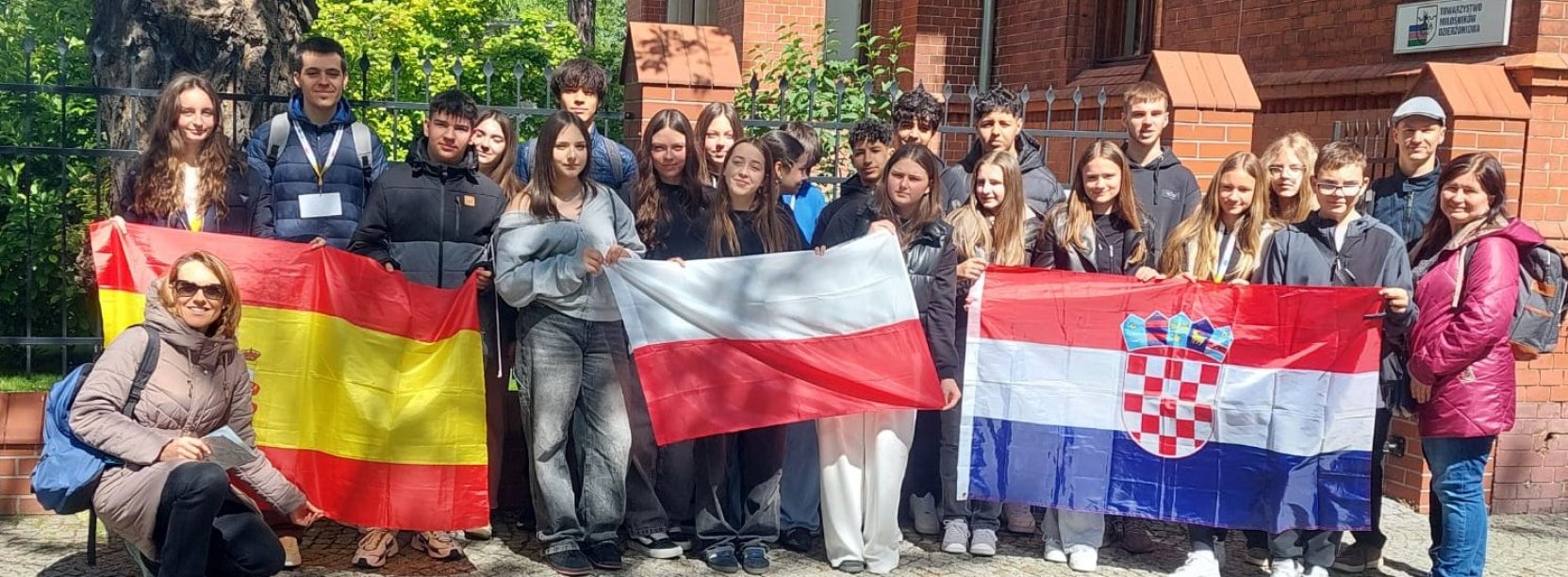 Grupowe zdjęcie uczniów trzymających flagi Polski, Chorwacji i Hiszpanii