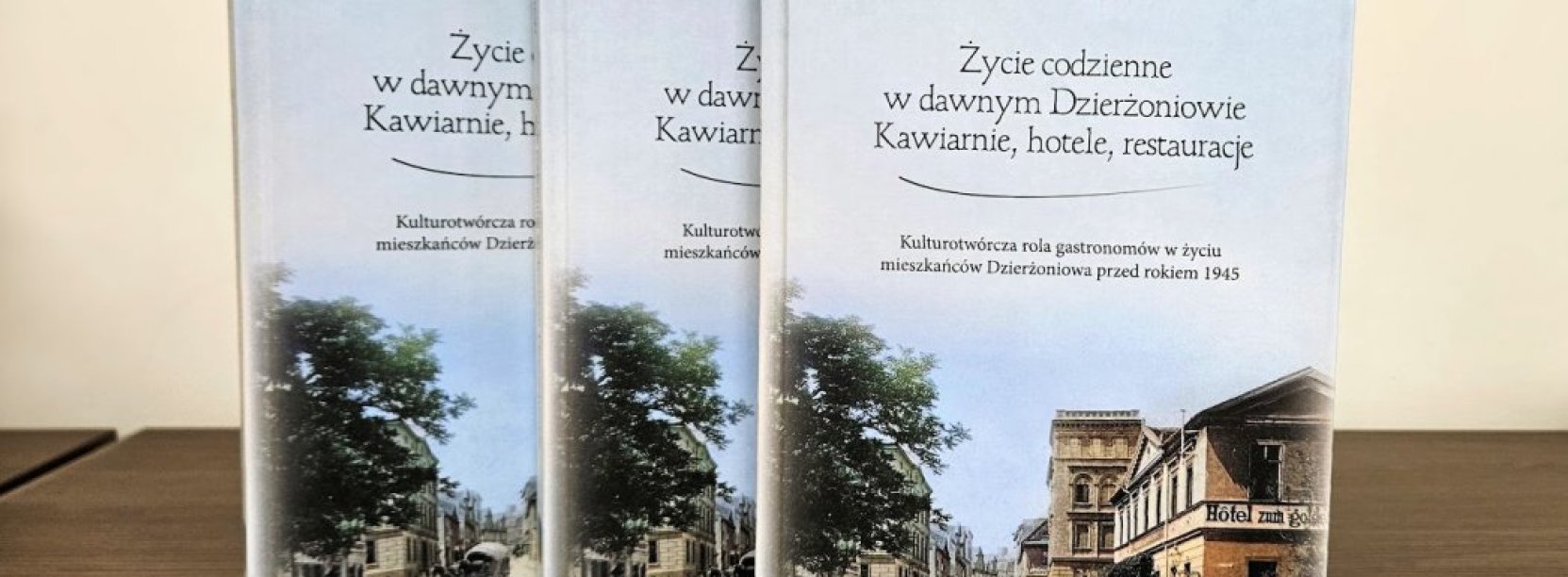 Trzy książki ustawione obok siebie, na okładce historyczne zdjęcie jednej z ulic Dzierżoniowa