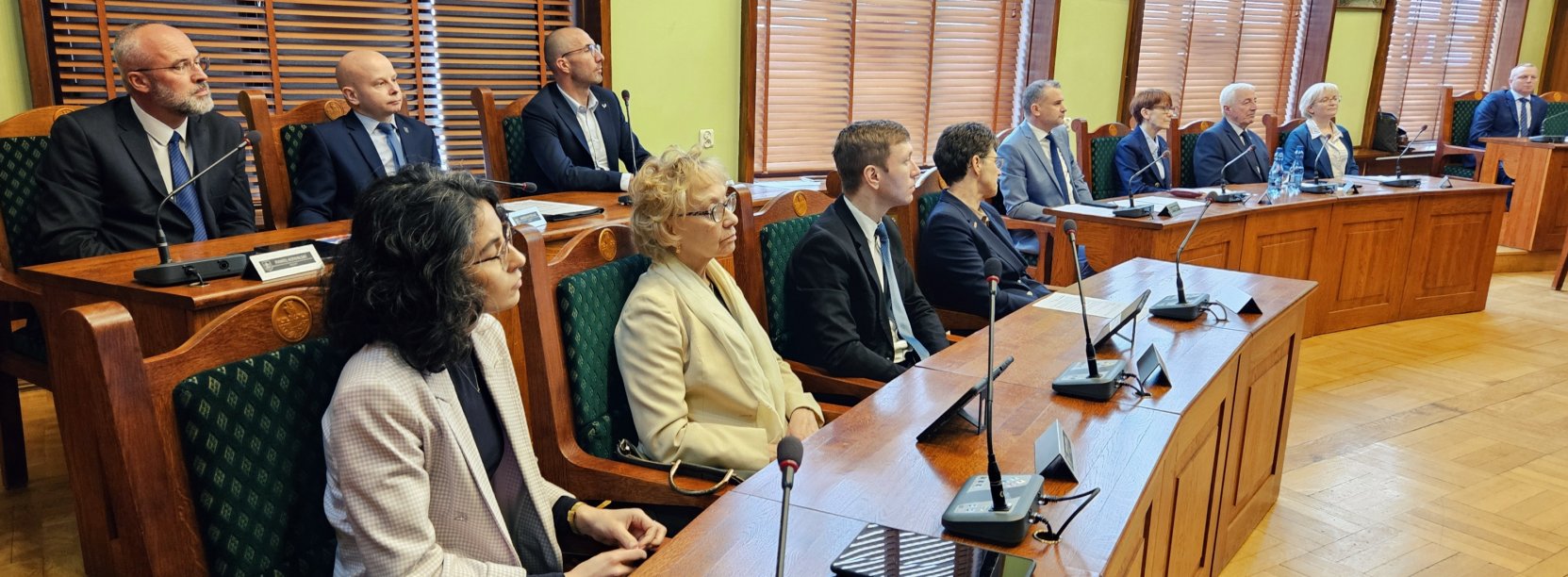 Radni przy stołach zmikrofonami podczas sesji