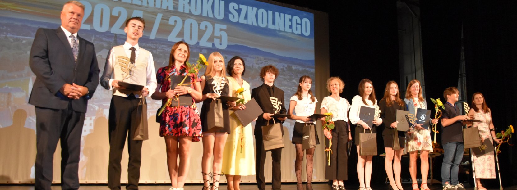 Kilkunastu uczniów na scenie na wspólnym zdjęciu z burmistrzem