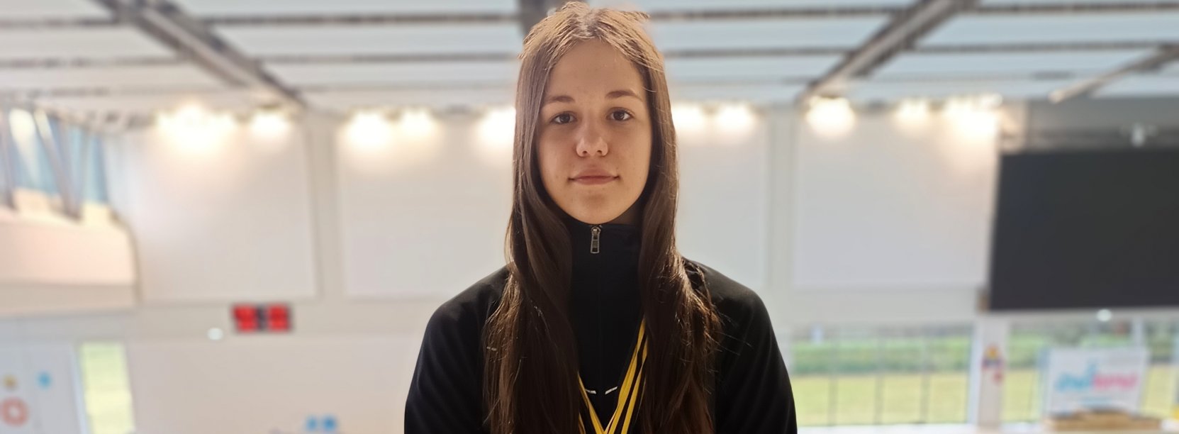 Natasza Paraciej z medalami na szyi przy niecce basenu krytego